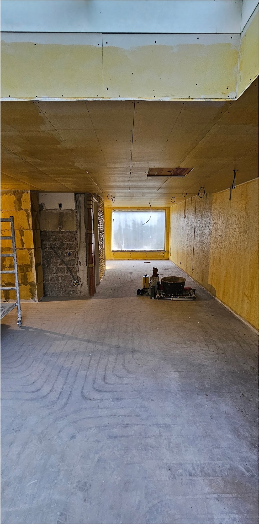 Grote ruimte voor het stucwerk, met vloerverwarmingsleidingen op de vloer
